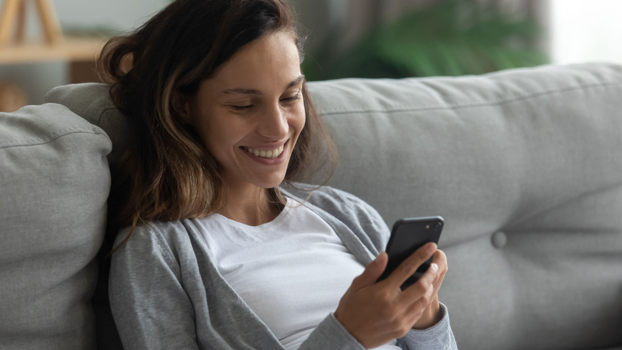 Woman using mobile phone on sofa