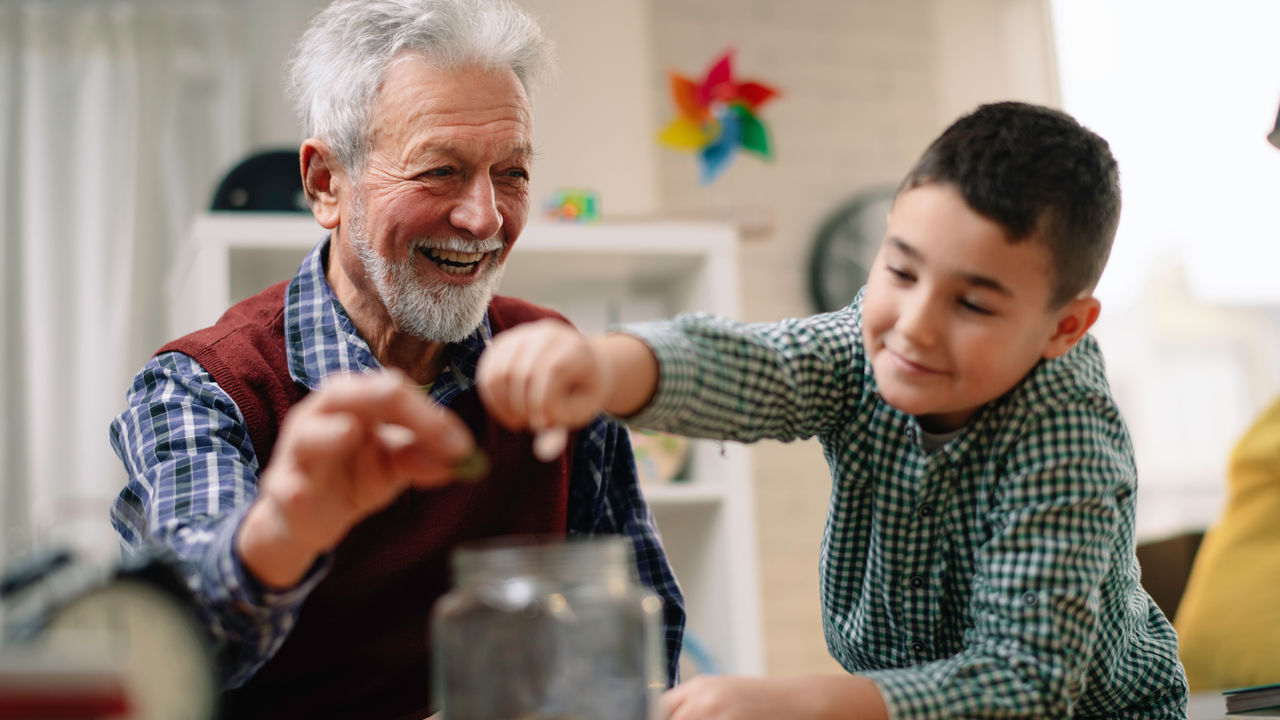child and grandparent putting coins in a jar