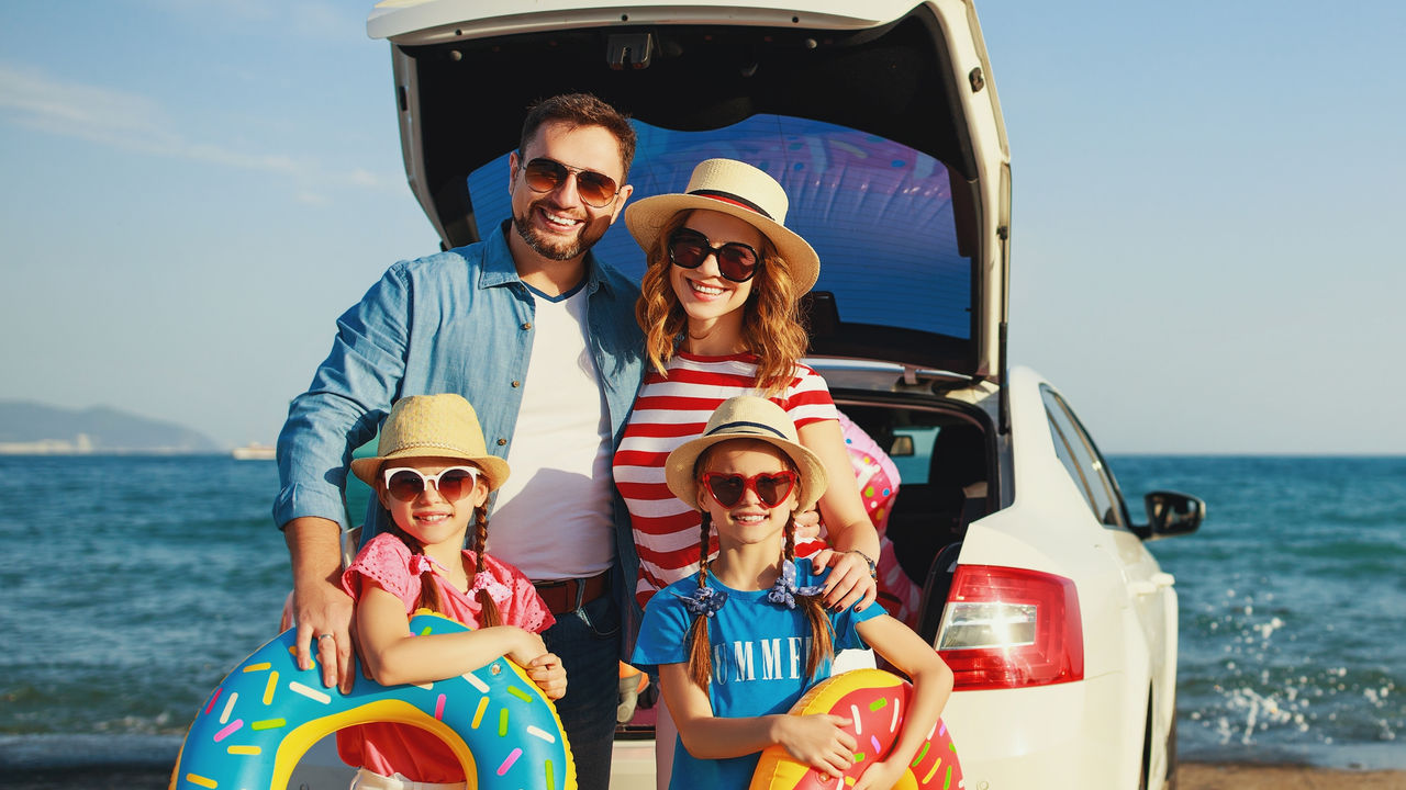 happy   family mother father and children in summer auto journey travel by car on beach&#xD;